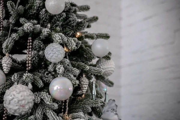 Close-up de uma árvore de Natal ao ar livre festivamente decorada com bolas em um fundo de fadas espumante borrado. Luzes de guirlanda desfocadas, efeito bokeh. — Fotografia de Stock