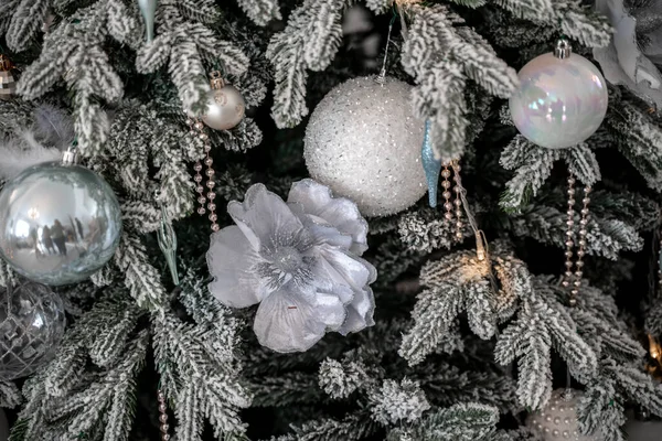 Primer plano de un árbol de Navidad al aire libre decorado festivamente con bolas sobre un fondo borroso y brillante. Luces de guirnalda desenfocadas, efecto bokeh. — Foto de Stock