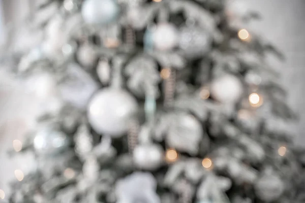 Close-up de uma árvore de Natal ao ar livre festivamente decorada com bolas em um fundo de fadas espumante borrado. Luzes de guirlanda desfocadas, efeito bokeh. — Fotografia de Stock