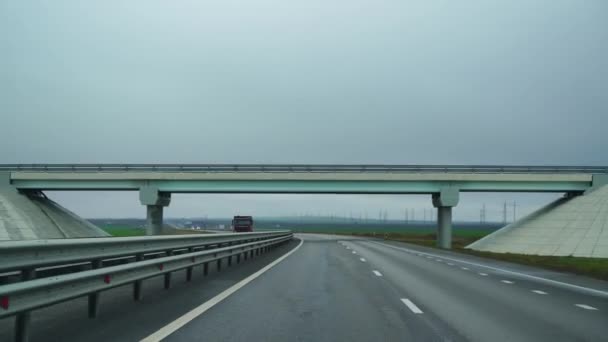 En bil kör längs en bred tom väg tidigt på morgonen i molnigt väder. Körning synvinkel, insidan av en bil på Autobahn — Stockvideo