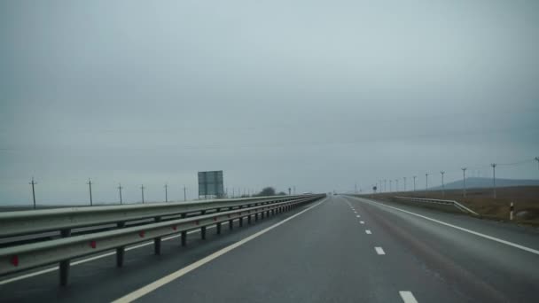 Um carro dirigindo ao longo de uma ampla estrada vazia no início da manhã em tempo nublado. Ponto de vista de condução, vista interior de um carro na Autobahn — Vídeo de Stock