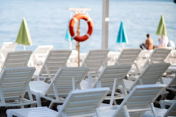 Kilku białych leżaków i parasol na bezludnej plaży. Idealny pomysł na wakacje. — Zdjęcie stockowe