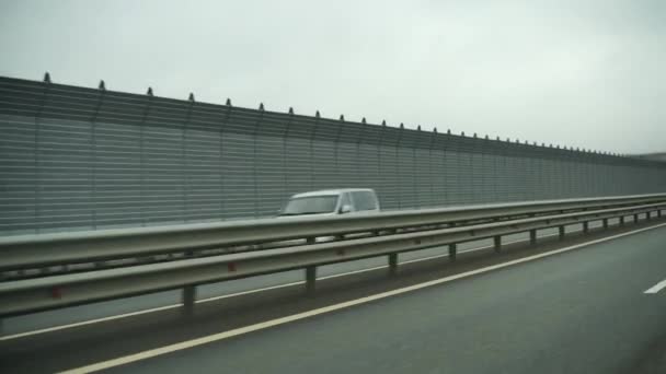 Un coche que conduce a lo largo de un amplio camino vacío temprano en la mañana en tiempo nublado. Punto de vista de conducción, vista interior de un coche en la Autobahn — Vídeo de stock