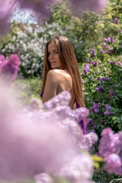 Portrait de jeune femme aux cheveux longs en plein air dans un jardin lilas en fleurs — Photo