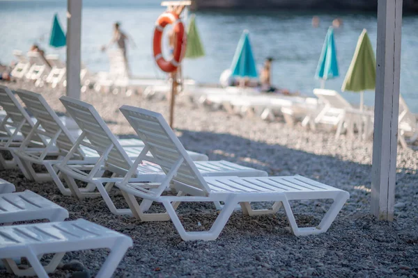 Lettini bianchi e un ombrellone su una spiaggia deserta. Il concetto di vacanza perfetta. — Foto Stock