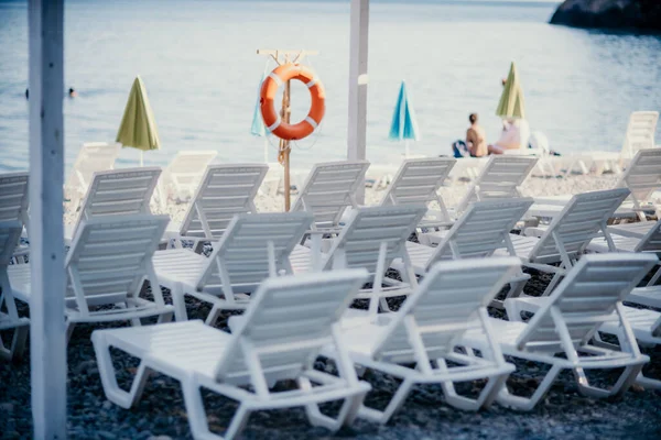 Kilku białych leżaków i parasol na bezludnej plaży. Idealny pomysł na wakacje. — Zdjęcie stockowe