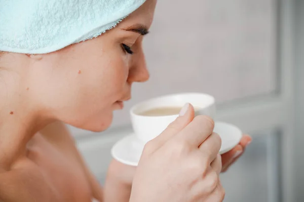 Jovem mulher relaxada serena em toalha de banho spa beber café de chá de bebida quente depois de tomar banho de chuveiro em casa. Tratamento de beleza, conceito de hidratação. — Fotografia de Stock