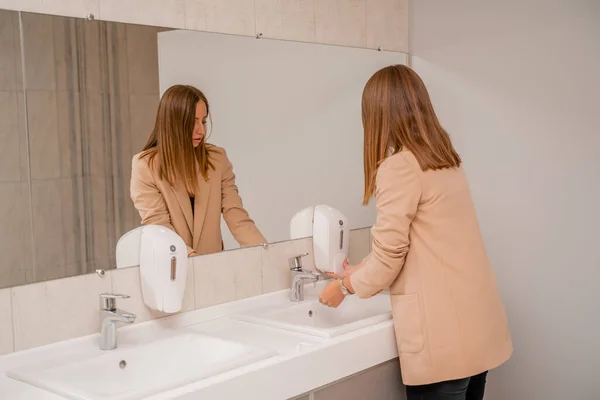 Žena si myje ruce pod tekoucí vodovodní vodou na veřejném záchodě. — Stock fotografie