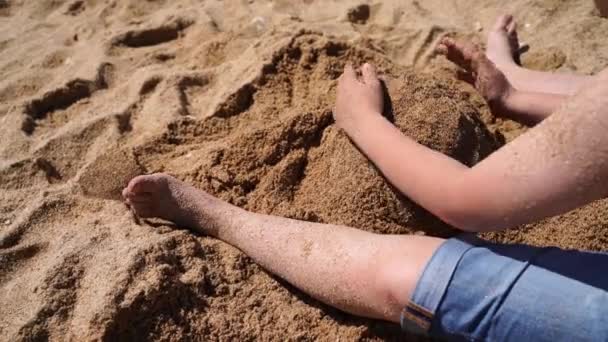 4К Вид сверху на ребенка зарывает ноги в песок — стоковое видео