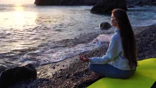 Achteraanzicht van een jonge mooie blanke vrouw die yoga beoefent op het strand aan de kust. Yoga! Een gezonde levensstijl. Meditatie-concept. — Stockvideo