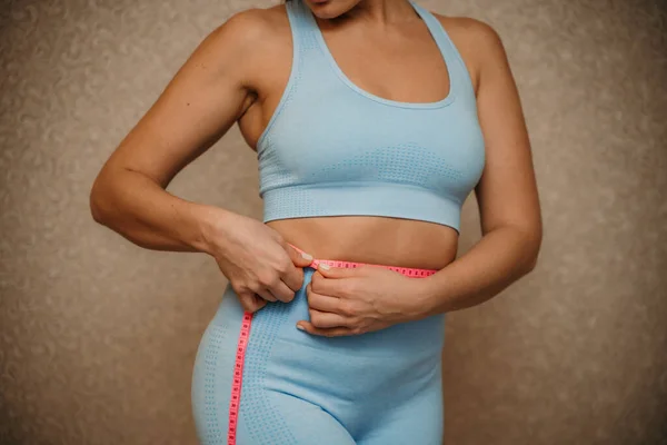 İnce bir kadının kemer ölçüsüyle belini kesme görüntüsü, yakın çekim. Tanınmayan Avrupalı kadın içeride kilo kaybı ya da liposuction için diyet sonuçlarını kontrol ediyor — Stok fotoğraf