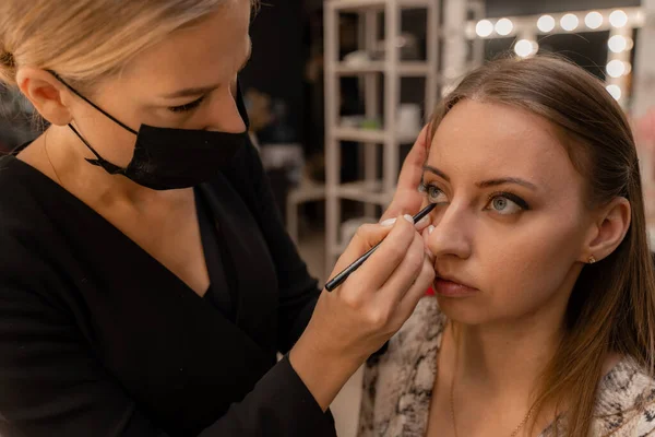 Maquillaje artista que trabaja con cepillo en los ojos del modelo Primer plano de la aplicación de maquillaje en la joven, semi perfil, maquillaje profesional en el estudio de belleza — Foto de Stock