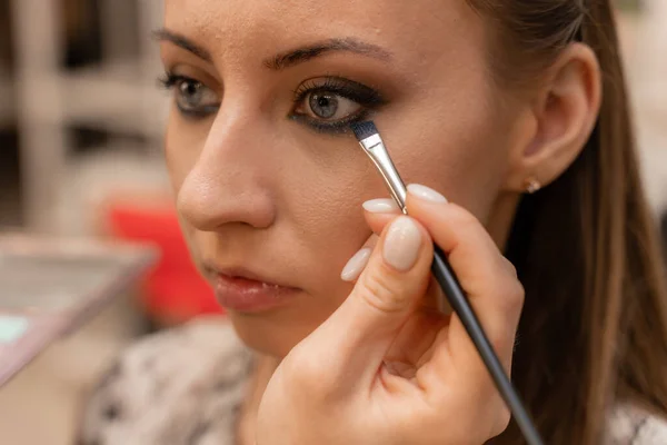 Maquiagem artista trabalhando com escova em olhos modelo Close up of applying make up on young girl, semi perfil, profissional make up in beauty studio — Fotografia de Stock