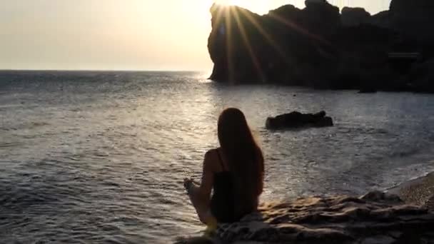 Selectieve focus. Achteraanzicht van een jonge mooie blanke vrouw die yoga beoefent op het strand bij zonsondergang aan zee. Yoga! Een gezonde levensstijl. Meditatie-concept. — Stockvideo