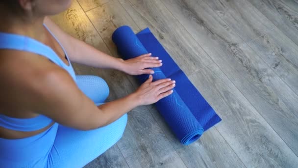 Het meisje gedraaid blauwe yoga mat na de training. — Stockvideo