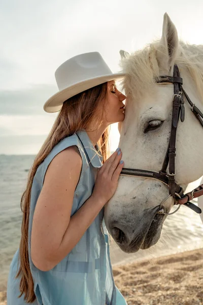 A young woman and a white horse against the background of the sky and the sea. — Stock Photo, Image