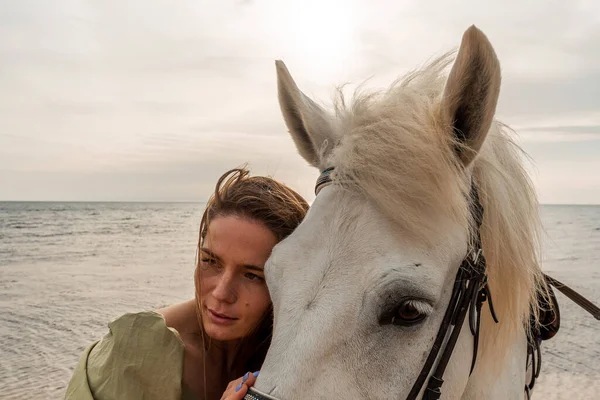 A young woman and a white horse against the background of the sky and the sea. — Stock Photo, Image