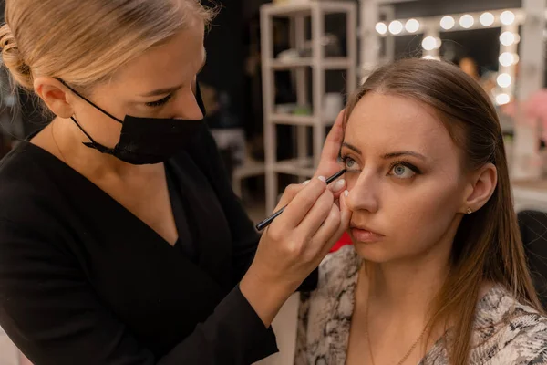 Maquiagem artista trabalhando com escova em olhos modelo Close up of applying make up on young girl, semi perfil, profissional make up in beauty studio — Fotografia de Stock