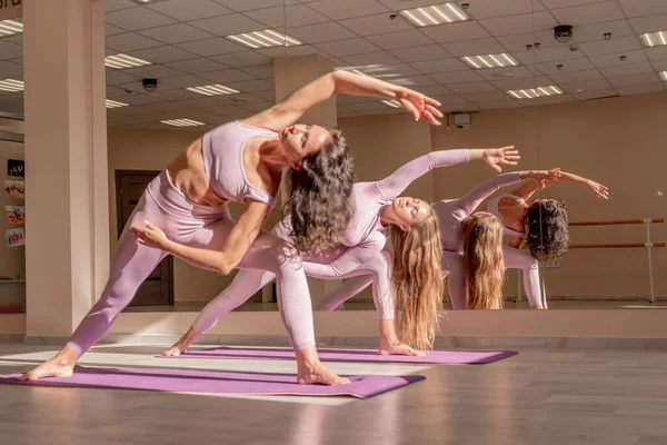 Duas mulheres bonitas cozinham fazendo ioga, esportes juntos no ginásio. Vestido com fatos cor de rosa. O conceito de graça e beleza do corpo. — Fotografia de Stock