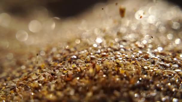 Close-up of sand pouring slowly, against the background of golden bokeh, sunset light. Slow motion. — Stock Video