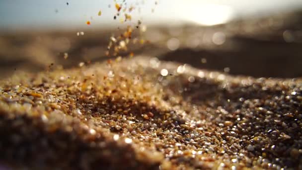 Close-up of sand pouring slowly, against the background of golden bokeh, sunset light. Slow motion. — Stock Video