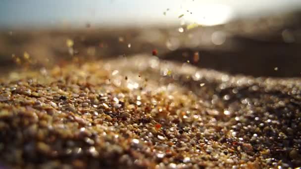 Close-up van zand gieten langzaam, tegen de achtergrond van gouden bokeh, zonsondergang licht. Langzame beweging. — Stockvideo