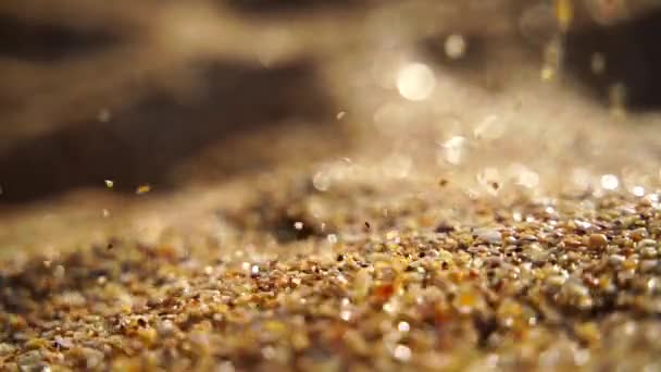 ゴールデンボケ,日没の光の背景に対してゆっくりと注ぐ砂のクローズアップ. スローモーション. — ストック動画