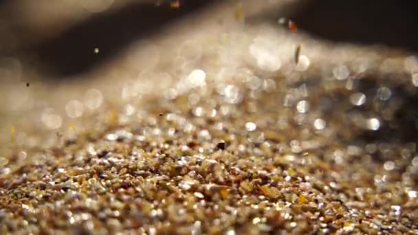 Close-up of sand pouring slowly, against the background of golden bokeh, sunset light. Slow motion. — Stock Video