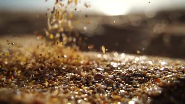 ゴールデンボケ 日没の光の背景に対してゆっくりと注ぐ砂のクローズアップ スローモーション — ストック動画
