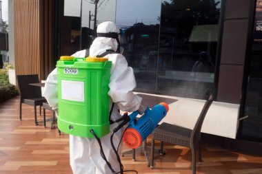 CHIANGMAI, THAILAND-APRIL 30, 2022 : Staff PPE uniforms suit are using an alcohol sprayer to clean the coronavirus in the street. Chiang Mai , Thailand.