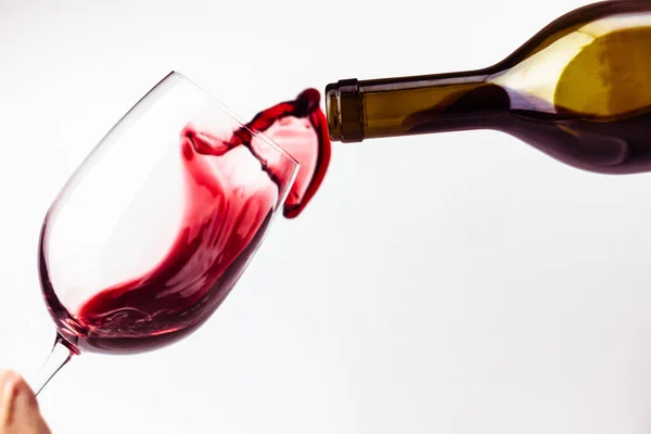 stock image Red wine pouring in the glass on white background close up. Splashes and  drops of wine. Alcohol drink