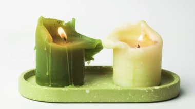 Beyaz arka planda mum yakmak. Mumlar yanar ve yüksek çerçevelerde ışıklar söner. Seramik tabakta doğal mumlar