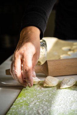 Kadınların elleri hamur ve patates püresinden hamur köftesi yapıyor. Ukrayna usulü Ukrayna usulü vareniki pişirme süreci. Mutfak gereçleri, hamur ve el yapımı hamur köfteleri masada.