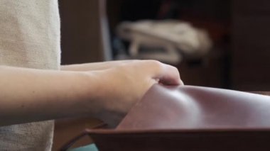Deri üretim atölyesi. Genç bayan terzi deri el yapımı çanta üzerinde çalışıyor. Atölyede çalışan deri ustası.