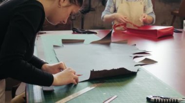 Deri üretim atölyesi. Genç bayan terzi deri el yapımı çanta üzerinde çalışıyor. Atölyede çalışan deri ustası.