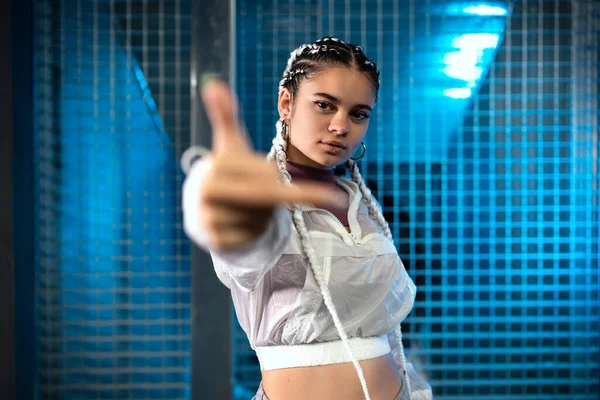 Mujer joven mostrando el dedo medio de lado a la cámara con luz azul en el fondo — Foto de Stock