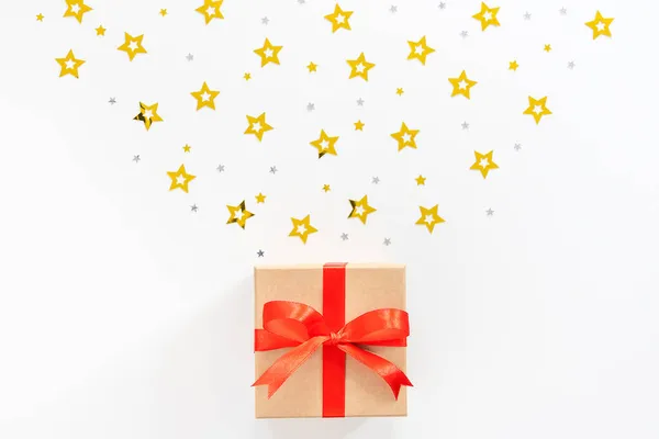 Caja de regalo con lazo rojo y estrellas sobre fondo blanco. — Foto de Stock