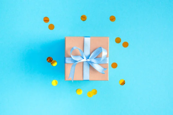 Caja de regalo sobre fondo azul con confeti. — Foto de Stock