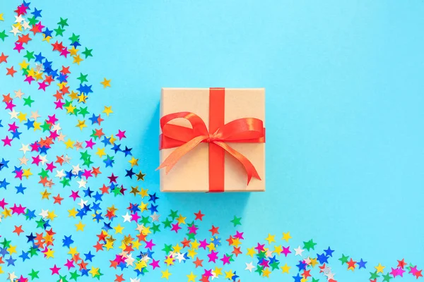 Caja de regalo sobre fondo azul con confeti. — Foto de Stock