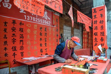 Foshan, Guangdong bölgesi, Çin. Ocak 14, 2022. İnsanlar Bahar Festivali için tebrik mektupları yazıyor. Foshan 'daki Kuaizi caddesinde Çin Yeni Yıl kutlamaları için hazırlık