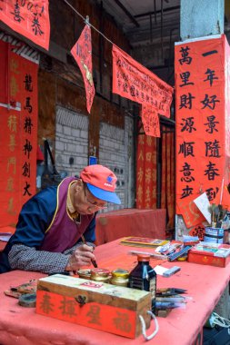 Foshan, Guangdong bölgesi, Çin. Ocak 14, 2022. İnsanlar Bahar Festivali için tebrik mektupları yazıyor. Foshan 'daki Kuaizi caddesinde Çin Yeni Yıl kutlamaları için hazırlık