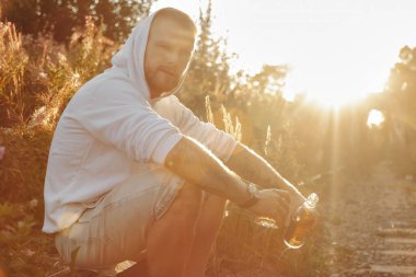 Genç adam gün batımında terk edilmiş bir demiryolunda alkol içiyor. Üzüntü, ilgisizlik, depresyon ya da yanlış yaşam tarzı kavramı. Boşluğu kopyala