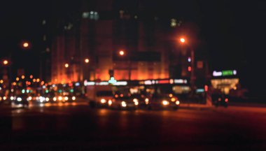 Gece sokağının araba ve sokak lambalarıyla soyut bir arka planı var. Şehir hayatı, şehrin odağından çıkmış ışıklar, tarz renk tonu. Tasarım için soyut stil kentsel altyapı kavramı. Boşluğu kopyala