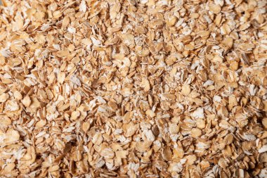 Arka planda bir yığın çiğ yulaf ezmesi yakın plan yulaf ezmesi. Makro fotoğraf yiyecekler çiğ yulaf ezmesi büyür. Doku arka planında tahıl tohumu inliyor. Yulaf lapası pişirmek için besin ürünü. Boşluğu kopyala