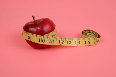the tailor's meter is wrapped around an apple.the concept of healthy eating.the concept of weight control.