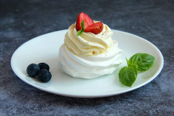 Tabakta ev yapımı Pavlova tatlısı. Kremalı Meringue Pavlova. Taze böğürtlen ve nane ile süslenmiş..