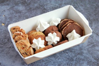 Tabakta çeşitli kurabiyeler var. Taze ev yapımı kurabiyeler: bisküviler, çikolatalı kurabiyeler, şekerli kurabiyeler, meringe, fındıklı kurabiyeler, karamel kurabiyeleri, kakao kurabiyeleri