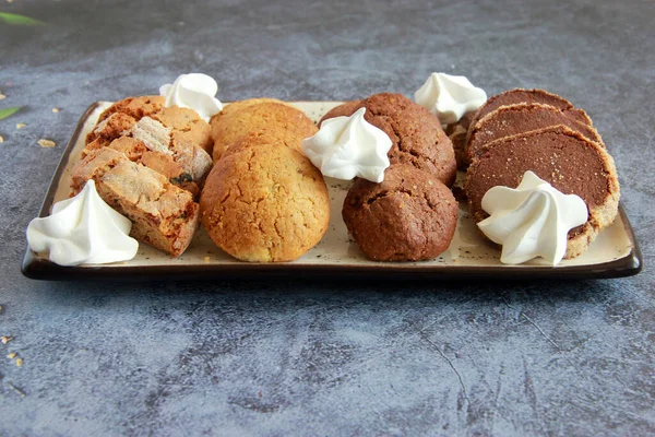 Assorted cookies on the plate. Fresh homemade cookies: biscotti, chocolate cookies, sugar cookies, meringe, nut cookies, caramel cookies, cocoa cookies