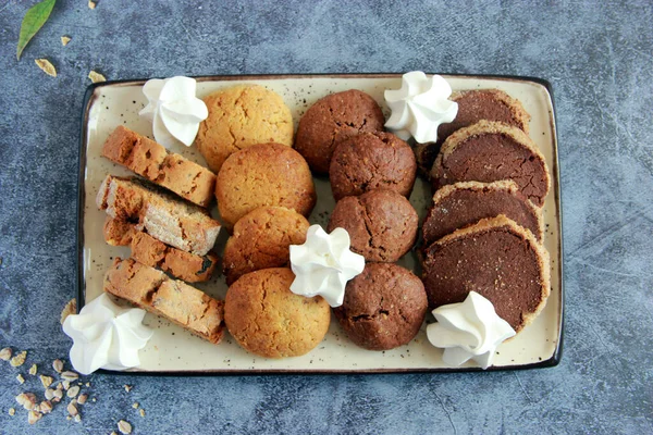 Assorted cookies on the plate. Fresh homemade cookies: biscotti, chocolate cookies, sugar cookies, meringe, nut cookies, caramel cookies, cocoa cookies