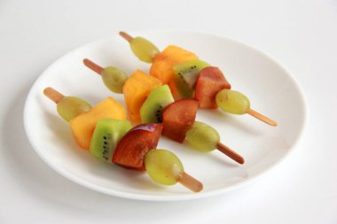 Taze meyvelerden yapılmış çocuk partisi için meyve kebabı. Taze kivi, erik, üzüm, ahşap çubuklarda hurma. Doğum günü partisi için egzotik meyve mezeleri..